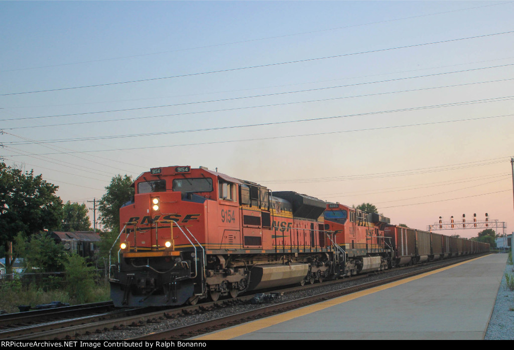 Eastbound loaded coal train passing the station at twilight 